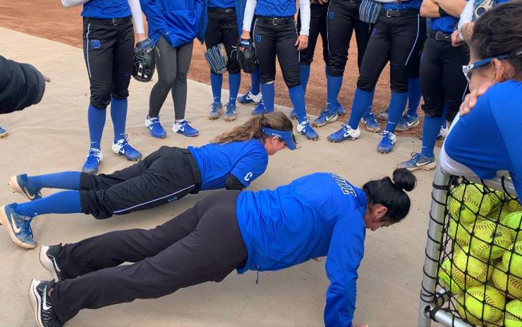 Student Raine Wilson, top, and softball coach Jessica Bracamonte, bottom, compete to do the most push-ups after a Duke Softball practice. Photo courtesy of Marissa Young.