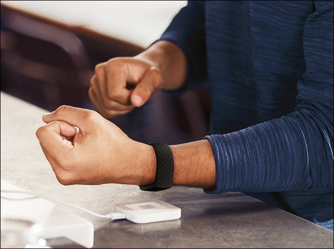 A man charging a Fitbit Charge 4.