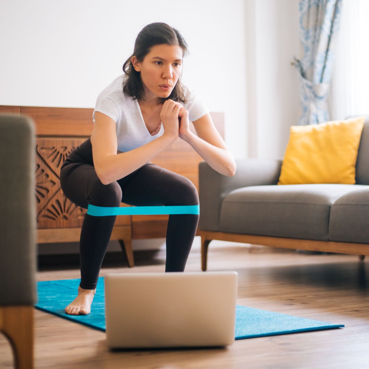 sporty young woman exercising at home with resistance band