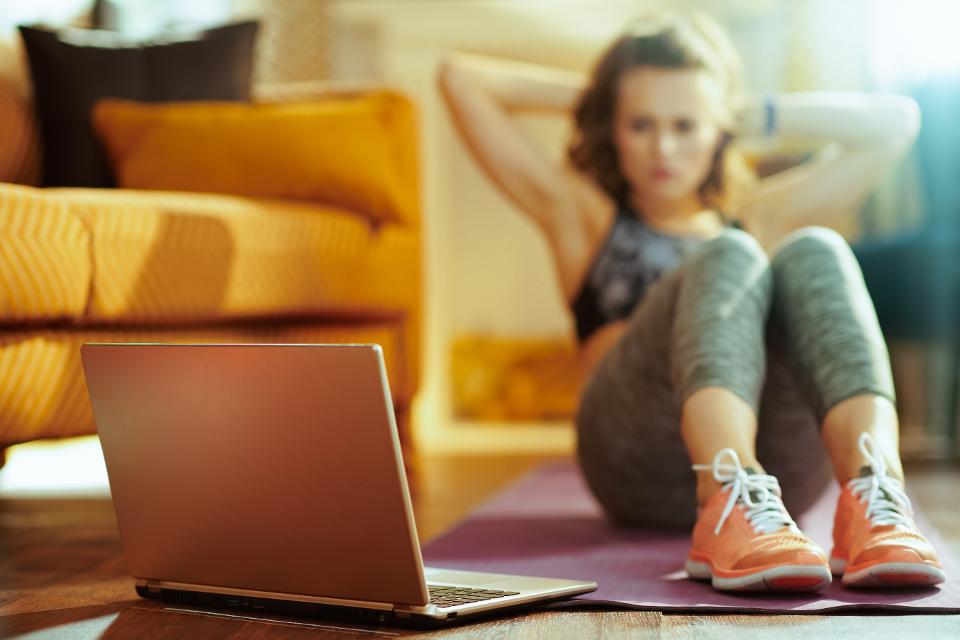 Closeup on laptop and woman doing abdominal crunches