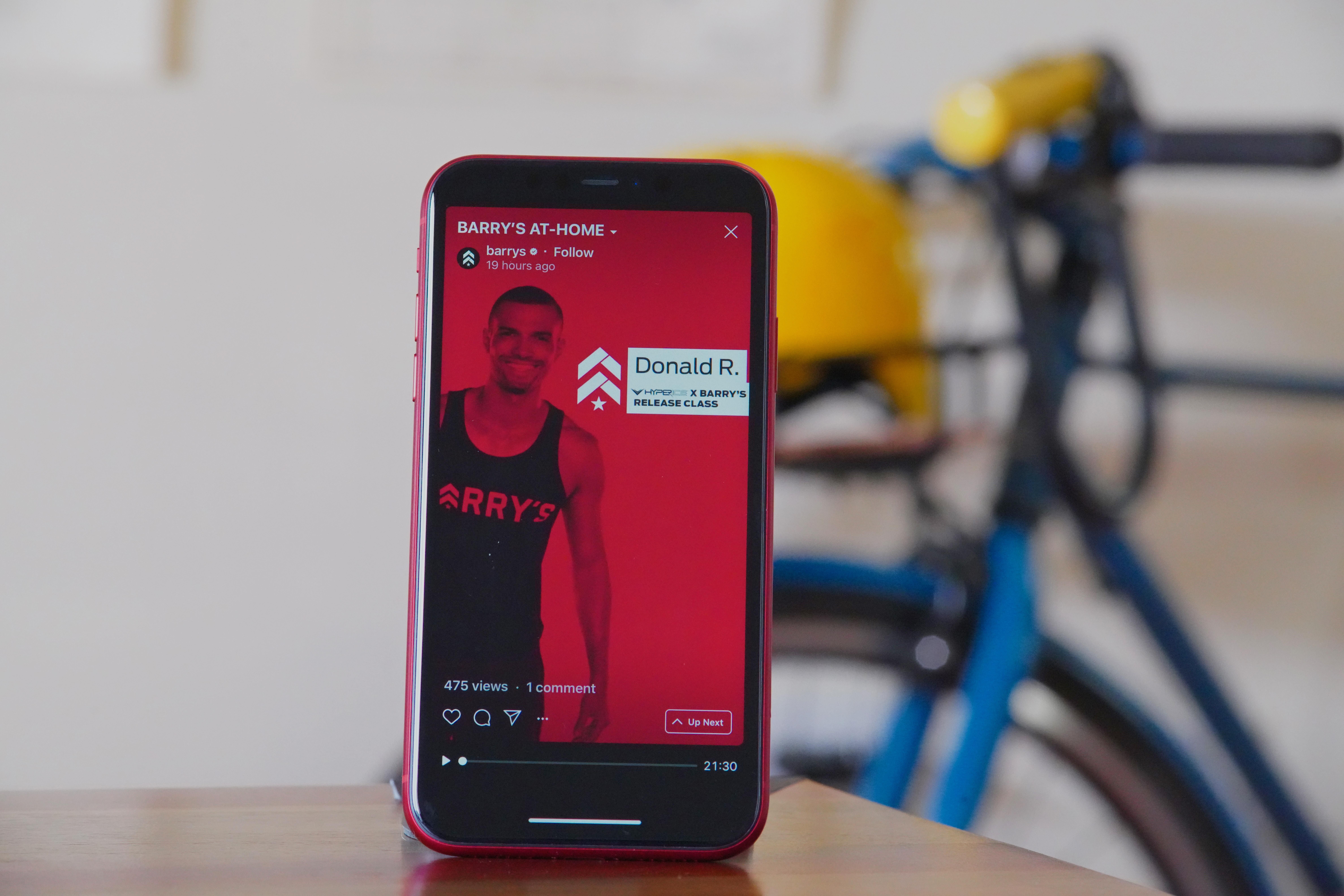 red iphone propped up on desk with a screen showing a workout video