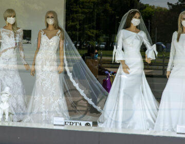 A cyclist wearing a coronavirus protective mask is reflected in a wedding dresses store window where mannequins also wear masks, in Zagreb, Croatia, Thursday, April 23, 2020. The store is closed because of Covid-19 lockdown. (AP Photo/Darko Bandic)